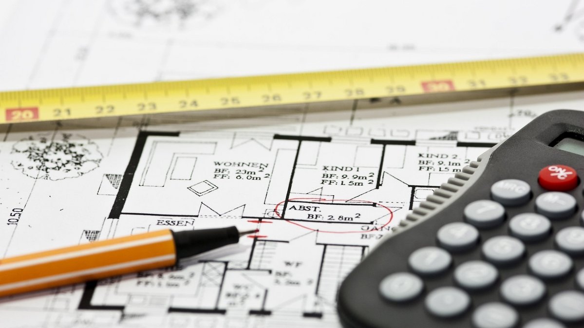 Bauplan mit Maßband und Taschenrechner zur Finanzierungsplanung beim Hausbau mit AN Massivhaus
