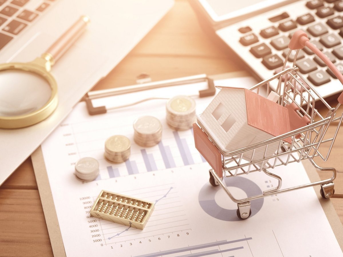 Baufinanzierung mit Hausmodell, Taschenrechner und Unterlagen für den Hausbau