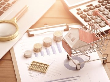 Baufinanzierung mit Hausmodell, Taschenrechner und Unterlagen für den Hausbau